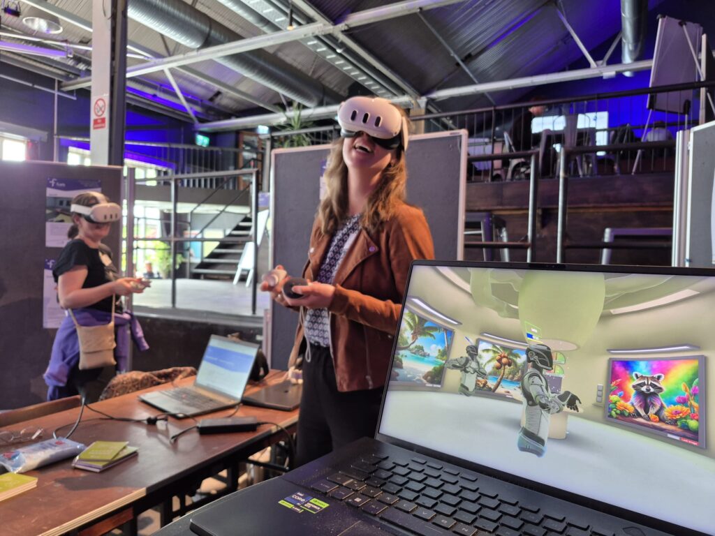 Im Vordergrund ein Laptop mit VR-Anwendung und im Hintergrund zwei Personen mit VR-Brillen und Controllern.